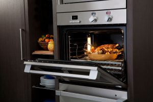 A large convection oven with a chicken and root veggies baking inside